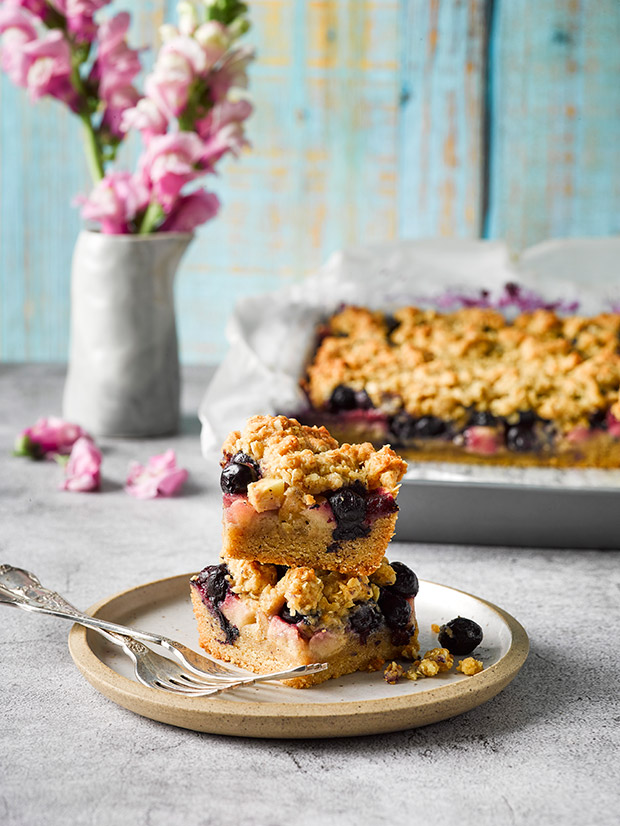 A stack of blueberry crumble slices sitting on a plate. 