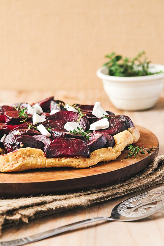 A beetroot and goat cheese tarte tatin served on a wooden chopping board. 