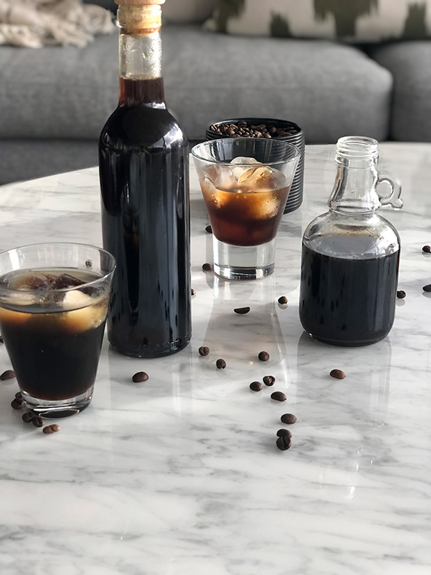 Bottles of homemade coffee liqueur with a shot glass of liqueur over ice.